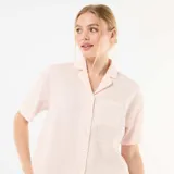 Pijama de dos piezas en color rosado y blanco a rayas finas, compuesto por una camisa de manga corta con cuello solapa, botones frontales y bolsillo en el pecho, y un short a juego con cintura elástica.