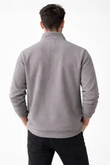 Buzo de polar negro con cuello alto y cierre frontal parcial, de manga larga y diseño holgado.
