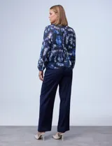 Blusa de gasa estampada con diseño circular en tonos azules, violetas y verde. Delantero plisado, puños elastizados, espalda con abertura ojal y botón.