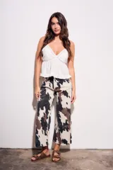 Pantalón de jean tiro medio, corte wide leg, con estampado que simula manchas de vaca en tonos beige, marrón y negro.