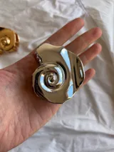 Pinza para el pelo plateada con forma de caracola.
