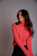 Polera de tejido de punto con cuello alto y diseño de trenzas verticales en el frente y las mangas. Es de manga larga y corte ajustado.