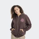 Campera con cierre frontal y capucha, color violeta, con diseño estampado de flores en el pecho y en la manga derecha. Posee bolsillos frontales tipo canguro y puños acanalados.