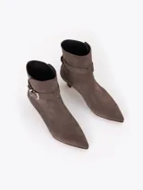 Bota de caña media confeccionada en cuero descarne, con punta fina, taco bajo forrado y detalle de tira con hebilla metálica en el tobillo.