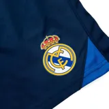 Short de fútbol azul marino con detalles en azul eléctrico y escudo del Real Madrid bordado en la pierna derecha.