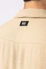 Camisa de manga corta color negro, con cuello cubano y botones frontales. Tejido de lino con textura entramada.