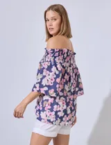 Blusa de gasa estampada con flores rosas y verdes sobre fondo azul marino. Escote bote con punto smock y mangas cortas amplias.