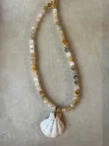 Collar largo de cuentas de piedras semipreciosas en tonos tierra, con dijes de conchas marinas.