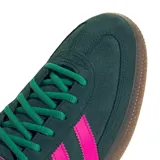 Championes Adidas Handball Spezial de gamuza verde oscuro, con las tres franjas laterales y el talón en fucsia. Presenta la inscripción dorada "SPEZIAL" en el lateral, suela de goma caramelo y cordones verdes.