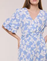 Vestido midi de calce holgado y caída fluida con escote en V cruzado, cintura elastizada fruncida y mangas cortas con volados superpuestos. Cuenta con un diseño estampado de flores grandes en tonos amarillo, blanco, azul marino y verde.