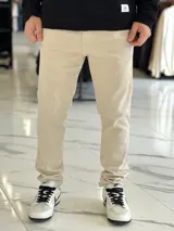 Pantalón de jean color beige, de corte regular y estilo chupín.