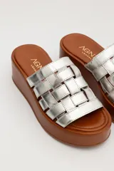 Sandalias de cuero color marrón con plataforma de madera y tiras de cuero plateado entretejidas.