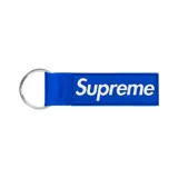 Llavero de cinta de tela azul con el logo de Supreme en relieve blanco y argolla metálica.