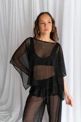 Conjunto de dos piezas de tul negro con apliques de pedrería brillante, compuesto por una blusa de mangas murciélago anchas y un pantalón recto translúcido.