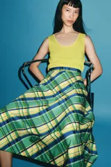 Falda midi de tiro medio marca ZWE Collection, confeccionada en hilatura de algodón con diseño de cuadros tipo tartán en tonos verdes, azules y amarillos. Tiene corte evasé y cierre lateral con cremallera oculta.