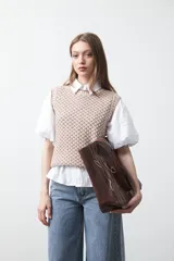 Chaleco tejido de algodón y acrílico, color beige y blanco, con un trabajo de punto que aporta textura. Diseño sin mangas y cuello redondo.