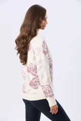 Buzo tejido en jacquard con estampado floral en tonos azul y marrón sobre base color crema. Presenta cuello redondo y puños acanalados.