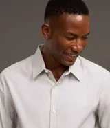 Camisa de vestir masculina de manga larga, confeccionada en tricolina con un sutil estampado de cuadros grid. Presenta cuello clásico, abotonadura frontal y puños con botones.