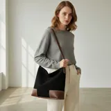 Bolso tipo hobo o shopper de eco cuero con textura símil gamuza, color negro con detalles en cuero marrón. Presenta costuras contrastantes en los detalles de cuero marrón en la base.