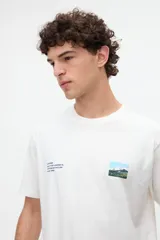 Remera de manga corta color blanco con diseño gráfico fotográfico y texto en el frente.