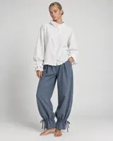 Pantalón azul deslizante de corte ancho, con cintura elástica y puños fruncidos ajustables mediante tiras atadas en los tobillos.