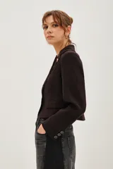 Saco de corte sastre entallado, color negro, con solapas clásicas, cierre frontal de un botón y mangas largas con detalle de botones en los puños.