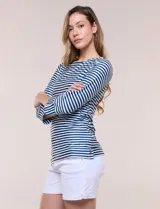 Remera de agua de silueta estilizada confeccionada en tejido técnico elastizado con protección solar UPF 50, con escote barco amplio y mangas 3/4 terminadas con puño en rayas verticales a contraste con pequeña abertura. Presenta aberturas laterales en el bajo decoradas con botones dorados grabados y ruedo recto de calce cómodo.