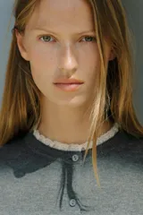 Chaqueta de punto color beige, de manga larga y corte corto, con cuello redondo y puños terminados en puntilla blanca a contraste.