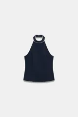 Top halter azul marino con detalles de ribetes en contraste color blanco en el cuello y el borde inferior, de diseño sin mangas y espalda descubierta con cierre de botones en el cuello.