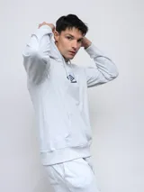 Canguro Umbro de felpa con capucha y cordones ajustables. Presenta el logo de la marca bordado en el pecho en color celeste y bolsillo frontal tipo canguro.