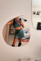 Top corto de cuero ovino color verde azulado con textura vintage, cuello halter y espalda descubierta con cierre de hebilla metálica. Combina con falda a juego.