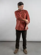 Camisa de corte regular, color terracota, de manga larga y diseño liso, con cuello camisero y cierre frontal de botones.