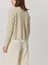 Saco abierto de punto con textura jaspeada en color gris oscuro, con bordes frontales en contraste color marrón. Presenta mangas largas y un corte recto.