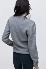Buzo de punto suave color gris, con cuello clásico estilo polo, tapeta con botones frontales, mangas largas y hombreras.