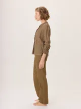 Camisa de lino rústico color marrón oscuro, con cuello mao, botones frontales y detalles de volados en el frente. Mangas largas con puños fruncidos.