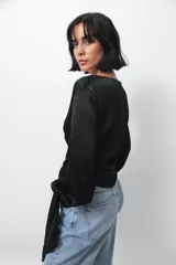 Camisa tipo blusa cruzada de seda negra, con escote en V profundo, mangas largas con puños abotonados y lazo lateral para anudar en la cintura.