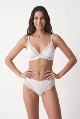 Colaless blanca de tejido acanalado con detalles de encaje floral en los laterales y placa metálica decorativa.