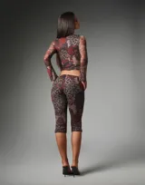 Conjunto de dos piezas de mesh elastizado con estampado floral y animal print, compuesto por un top corto de manga larga con cierre frontal de botones y abertura tipo lágrima, y un pantalón capri de tiro medio y calce ajustado.