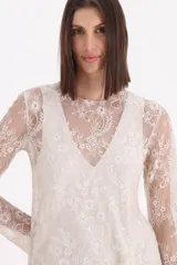 Blusa de encaje color beige, de manga larga y corte recto, con diseño floral detallado.