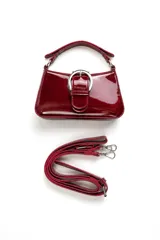 Cartera tipo bandolera de charol rojo, de diseño estructurado, con una hebilla metálica grande decorativa en el frente y correa larga ajustable y desmontable.