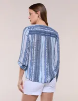 Blusa de gasa Zac & Rachel con estampado de rayas verticales en tonos rosados, amarillos y blancos. Presenta escote en V con cuello mao, cierre frontal con botones, un bolsillo aplicado en el pecho, mangas largas con presilla para regular el largo y detalle de nudo en el dobladillo inferior.