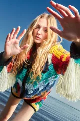 Cardigan tejido a mano con lana multicolor, con cierre frontal, cuello a la base, calce holgado y puños ajustados. Presenta flecos blancos en los puños y ruedo.