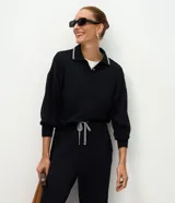 Buzo cerrado de algodón con cuello polo, mangas largas con puños ajustados y detalle de líneas contrastantes en el cuello.