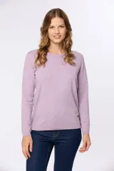 Buzo tejido en hilo de algodón color beige, con cuello redondo y manga larga. Presenta un corte clásico y un pequeño detalle metálico en la parte inferior izquierda.