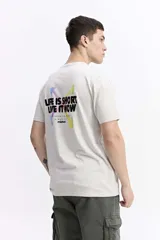 Remera de manga corta color blanco hueso con cuello redondo y fit regular. Estampado trasero con texto en negro y detalles de salpicaduras de pintura en tonos pastel (lila, amarillo, verde). Debajo del texto principal se lee "AUTHENTIC WEAR SINCE 1971 mistral".