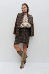 Chaqueta de lana en tono verde oliva con textura jaspeada, cuello mao y detalle de volado frontal. Presenta un corte entallado, bolsillos delanteros con solapa y cierre frontal con botones.