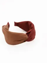 Vincha de tela con diseño de nudo central, combinando tonos marrón y bordó.