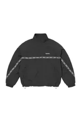 Campera de estilo deportivo Supreme, color negro, con cuello alto, cierre frontal completo y banda horizontal con logo estampado que recorre el pecho y las mangas. Cuenta con puños elásticos y cordón ajustable en el ruedo.