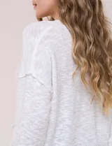 Cardigan blanco de punto liviano y texturado, de corte holgado y diseño casual. Cuenta con escote en V pronunciado, abotonadura frontal, mangas largas con hombros caídos y bolsillos delanteros tipo parche.