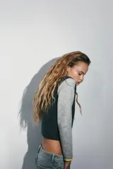 Chaqueta de punto con diseño color block, cuello redondo y manga larga. Presenta cuerpo en color gris oscuro, mangas en gris claro y detalles de ribetes en color amarillo vibrante. Cierre frontal con botones oscuros.